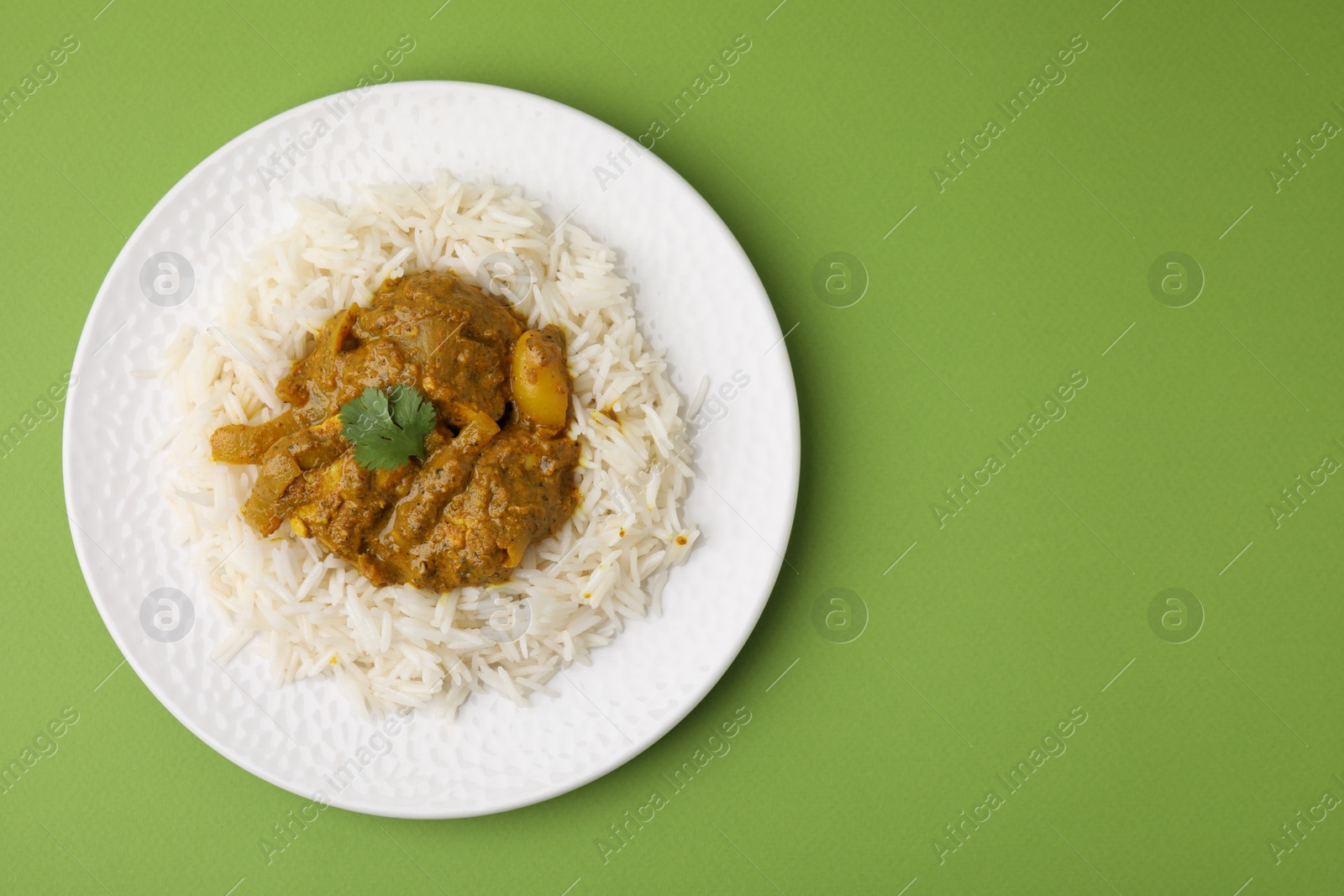 Photo of Delicious chicken curry with rice on green background, top view. Space for text