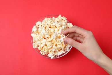 Photo of Woman eating popcorn on color background, top view