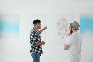 Men discussing artworks at exhibition in art gallery