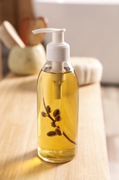 Photo of Dispenser with liquid soap on wooden table in bathroom