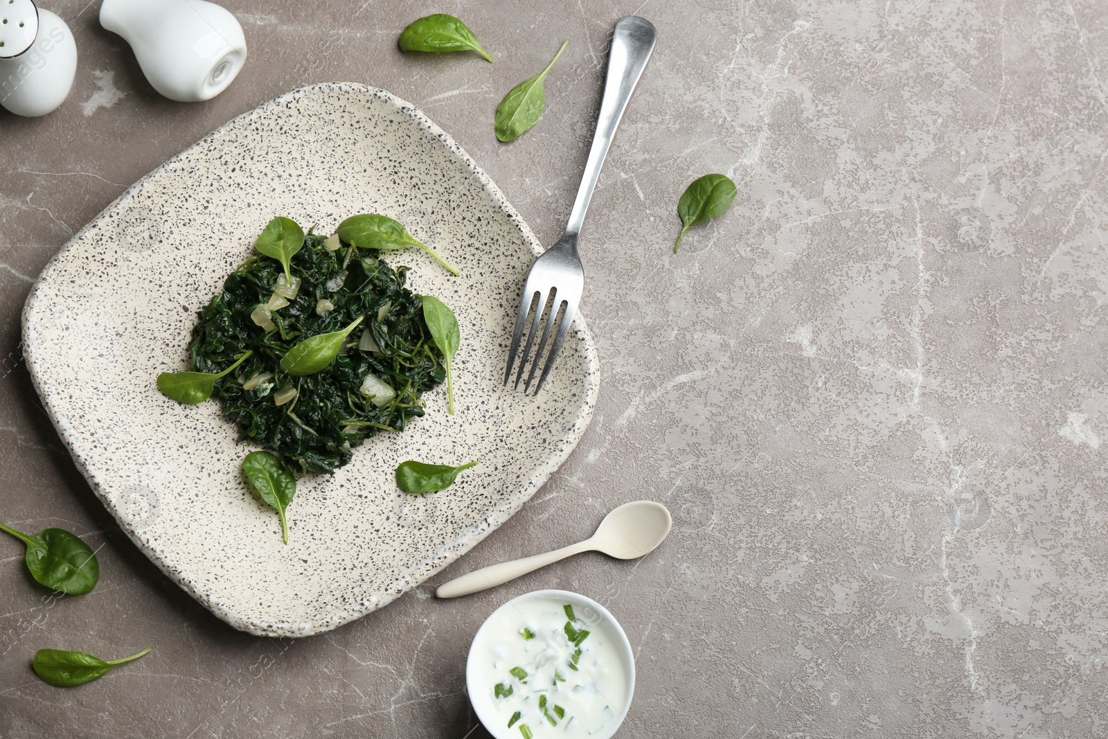 Photo of Flat lay composition with cooked spinach on grey marble table. Healthy food