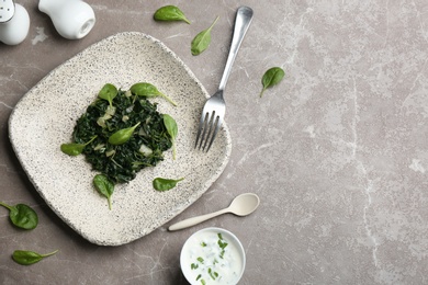 Flat lay composition with cooked spinach on grey marble table. Healthy food