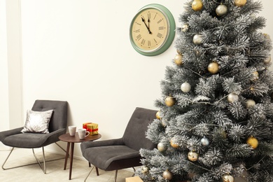 Stylish Christmas interior with decorated fir tree, table and chairs