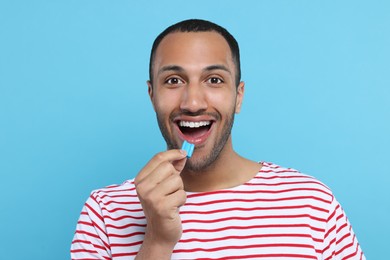 Photo of Portrait of happy young man with bubble gum on light blue background