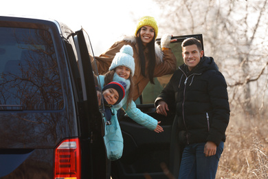 Photo of Happy man near modern car with his family outdoors