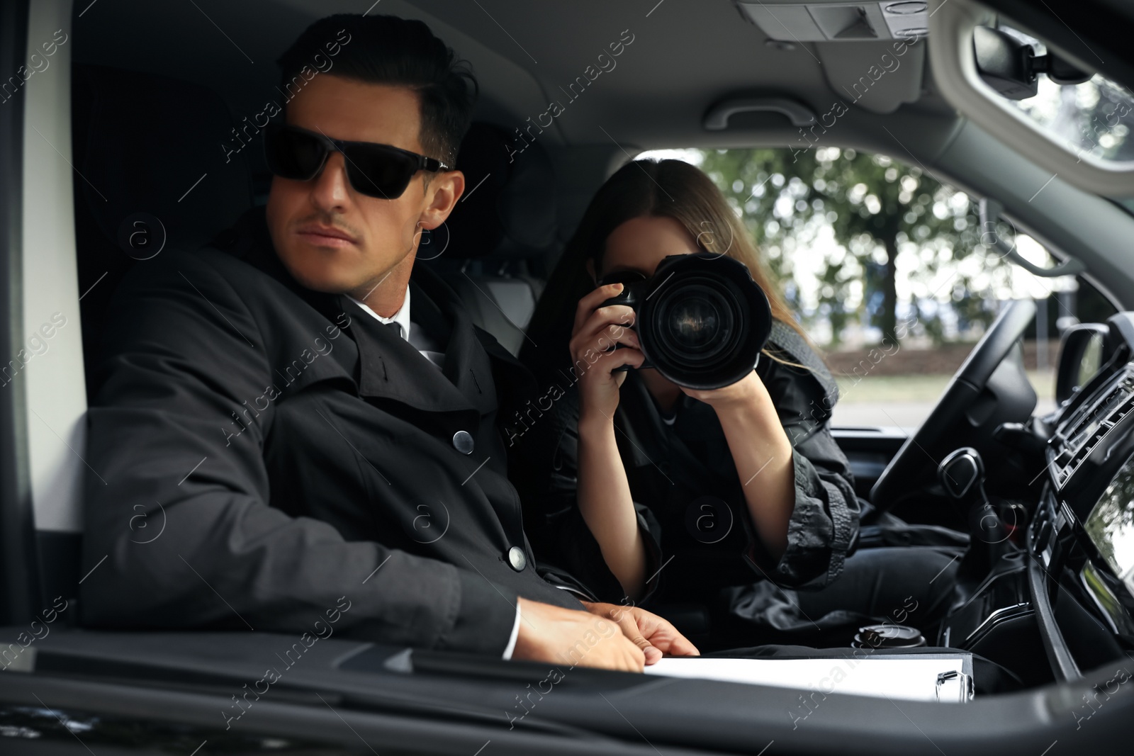 Photo of Private detectives with modern camera spying from car