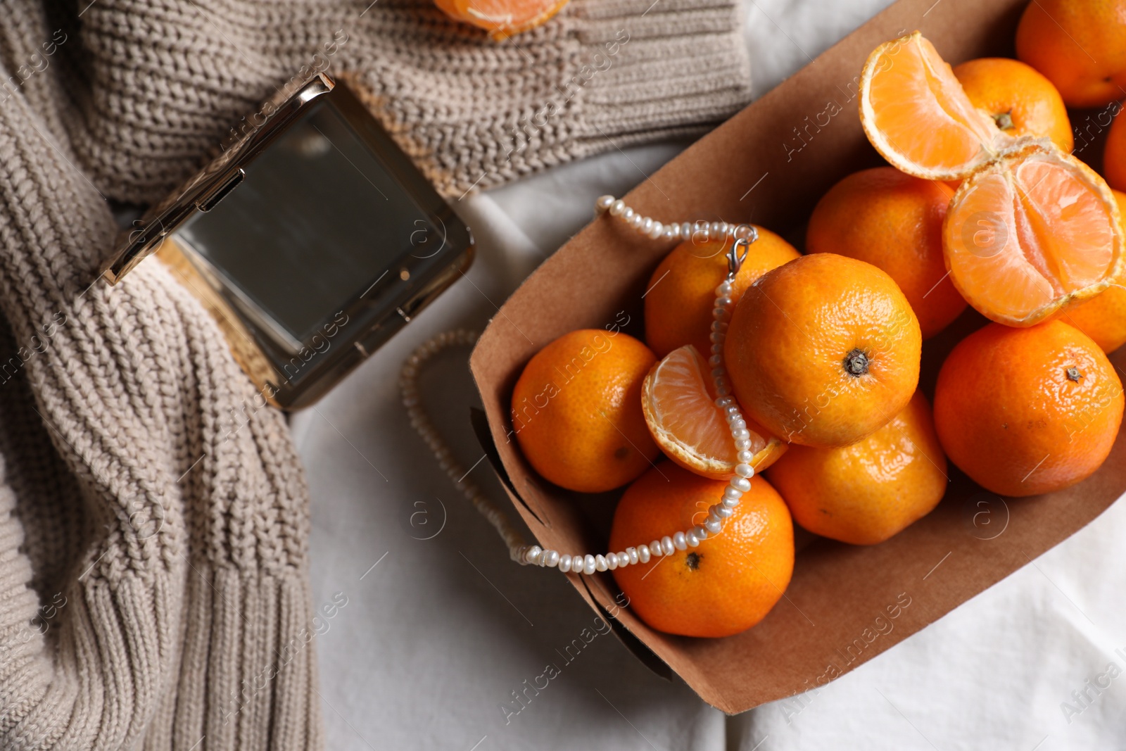 Photo of Paper box with fresh ripe tangerines and decor on white cloth, flat lay