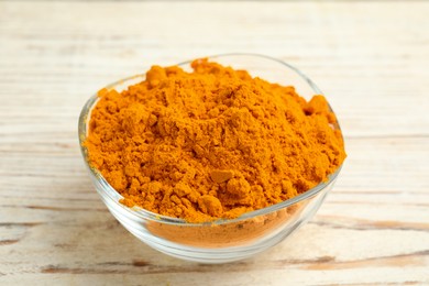 Photo of Aromatic saffron powder in bowl on white wooden table