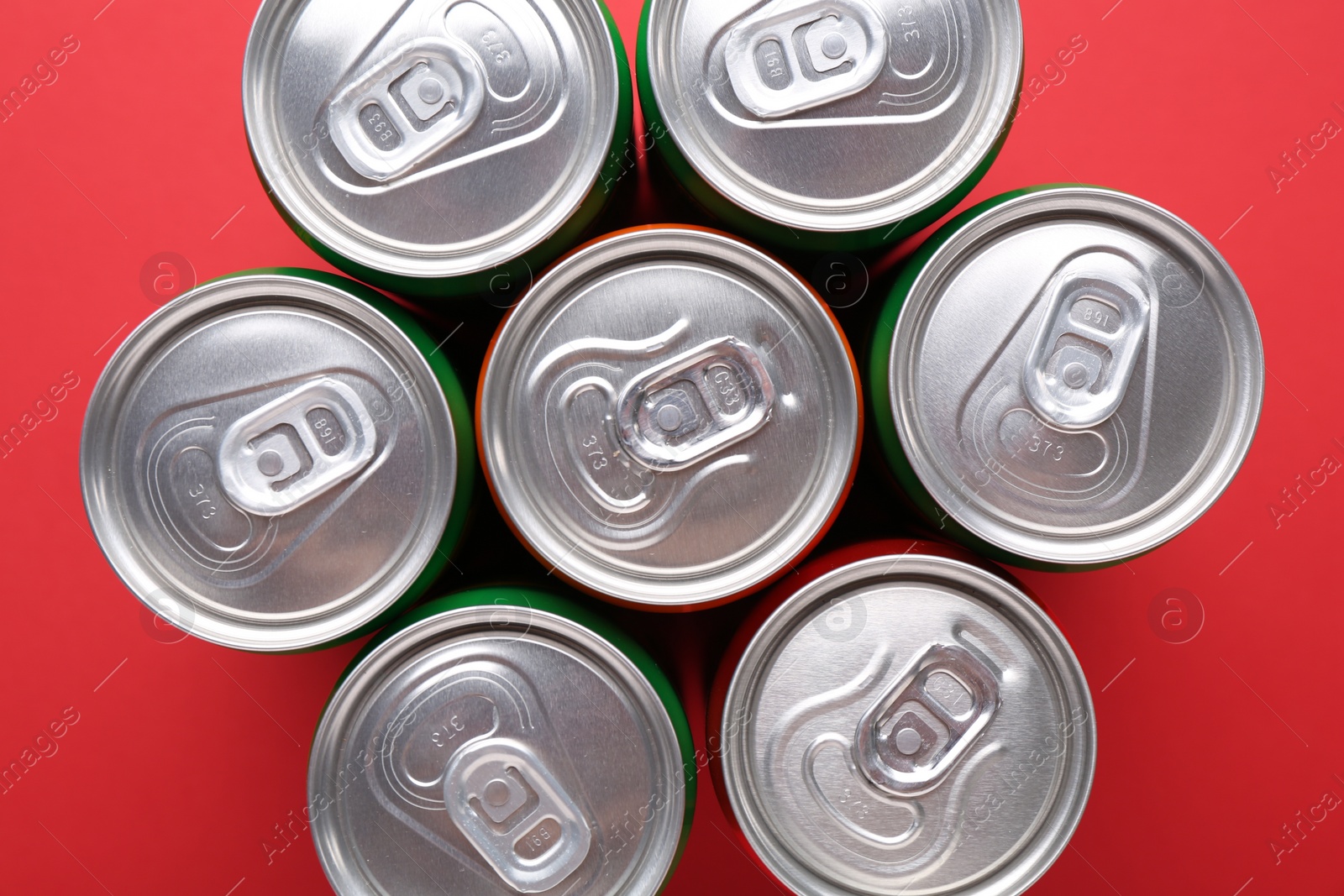 Photo of Energy drink in cans on red background, top view