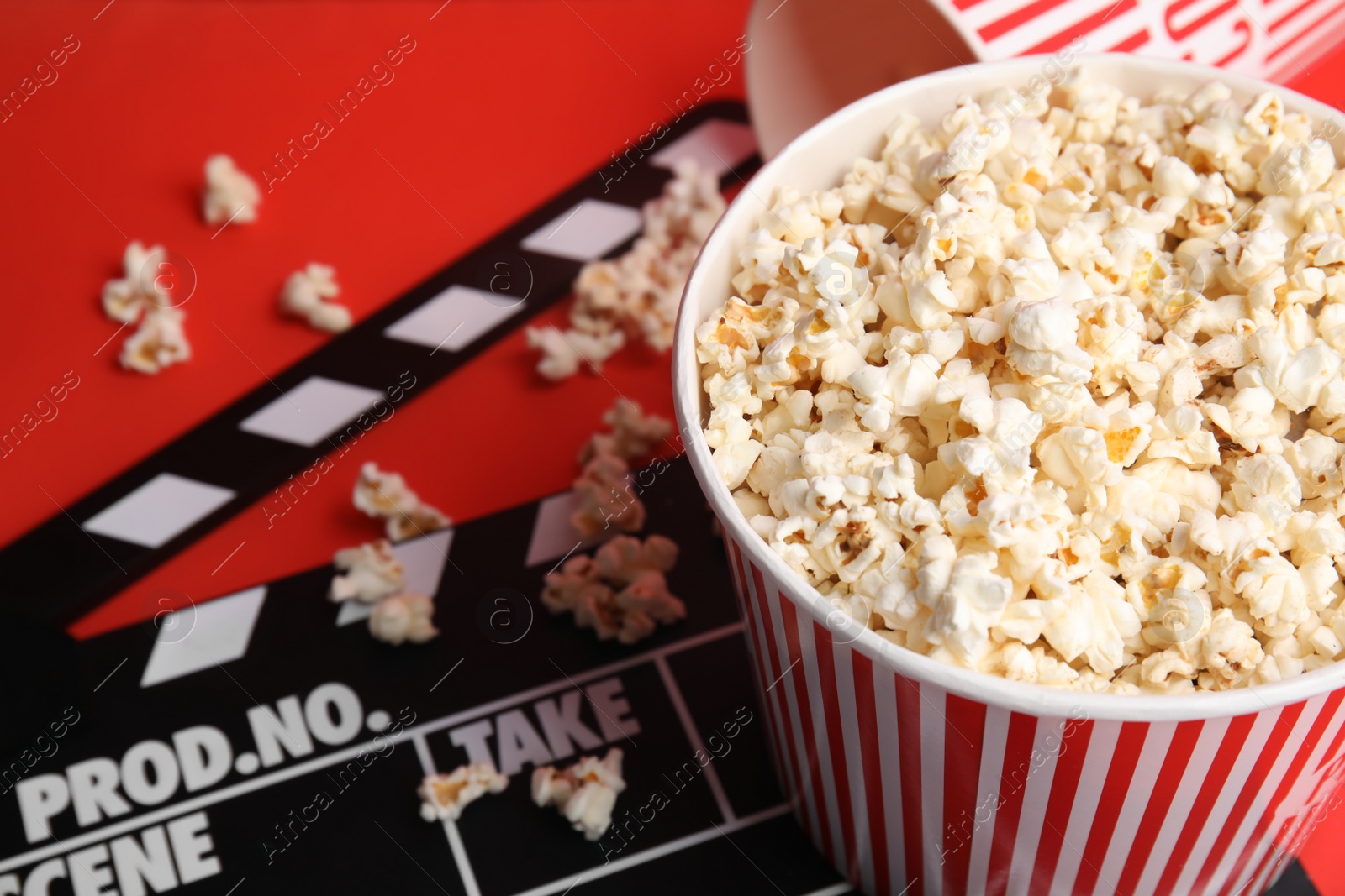 Photo of Tasty pop corn and clapboard on red background