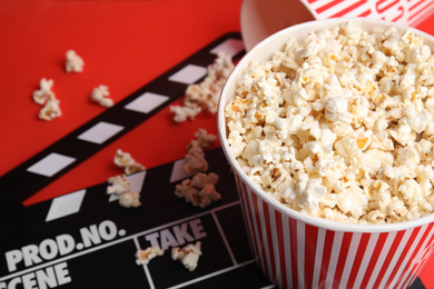 Tasty pop corn and clapboard on red background