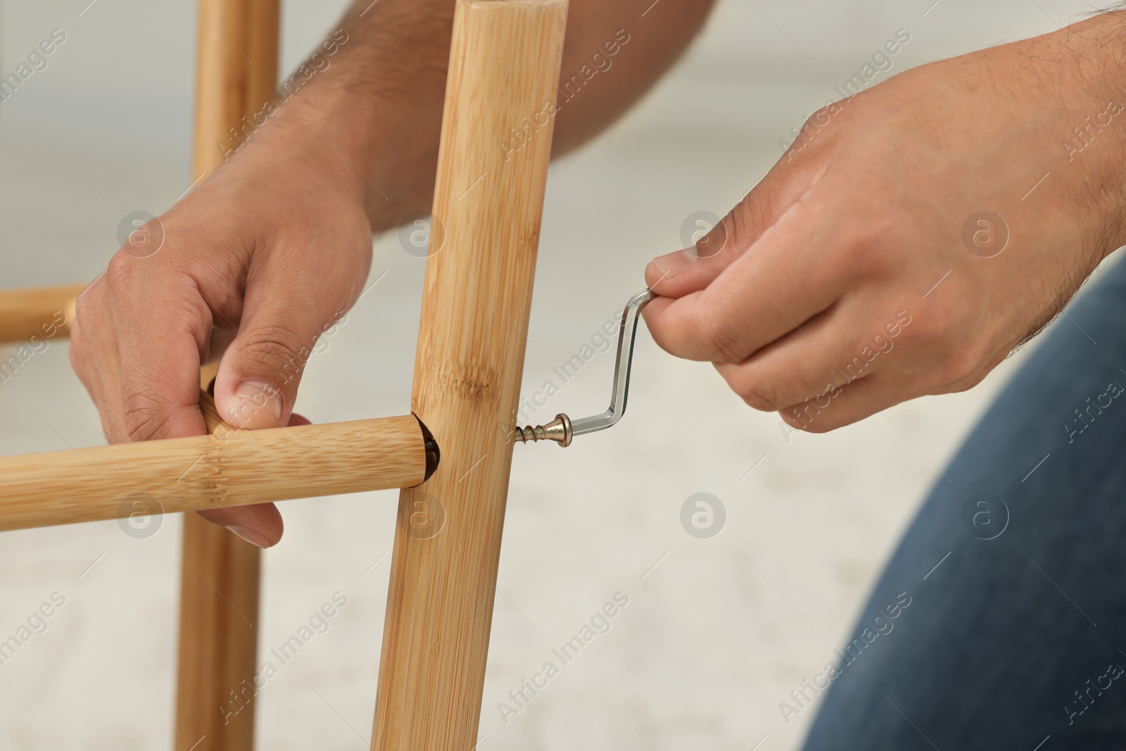 Photo of Man with hex key assembling furniture indoors, closeup