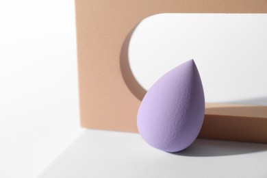 Photo of Stylish presentation of violet makeup sponge on white background, space for text