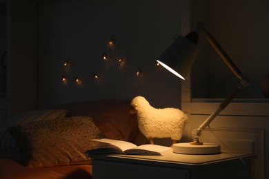 Photo of Lamp glowing on nightstand in cozy bedroom