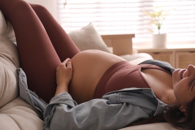 Photo of Pregnant young woman with big belly lying on sofa at home