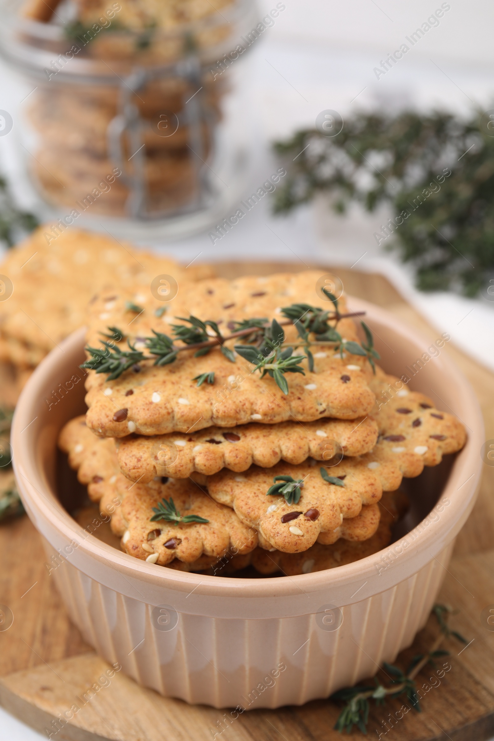 Photo of Cereal crackers with flax, sesame seeds and thyme in bowl on table, closeup
