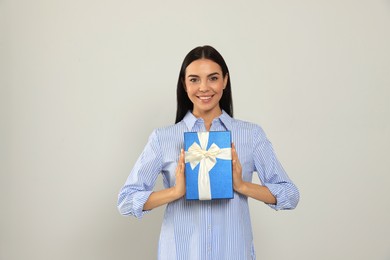 Photo of Happy young woman holding gift box on light grey background