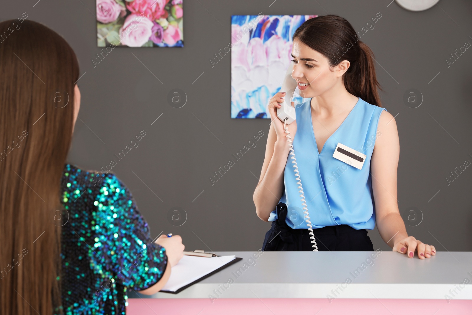 Photo of Young receptionist and client at desk in beauty salon