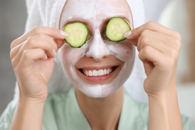 Photo of Woman with face mask and cucumber slices on blurred background, closeup. Spa treatments