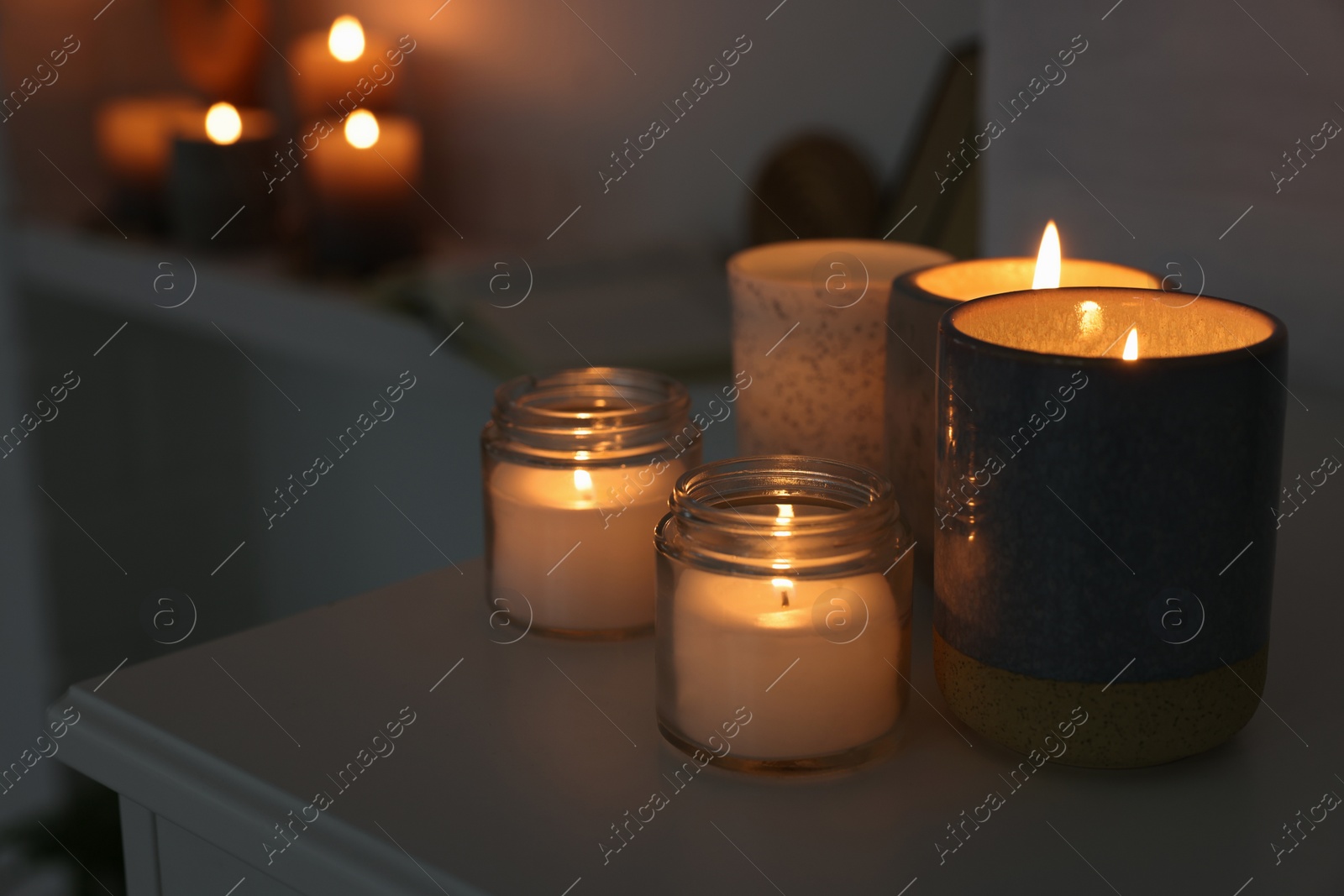 Photo of Burning wax candles on white table in room, space for text
