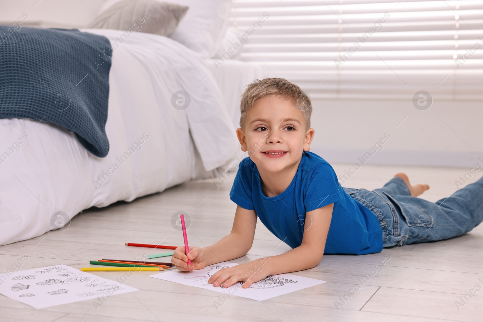 Photo of Cute little boy coloring on warm floor at home. Heating system