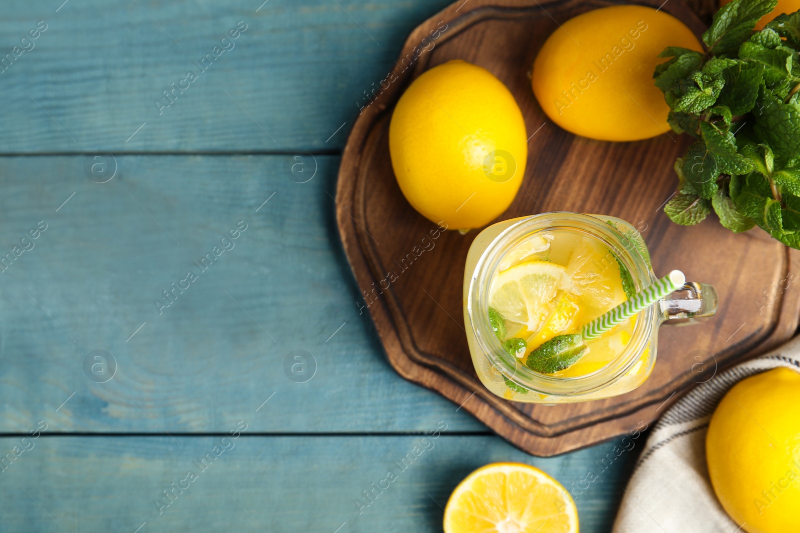 Photo of Cool freshly made lemonade and fruits on light blue wooden table, flat lay. Space for text