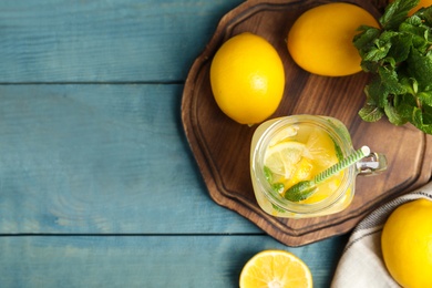 Photo of Cool freshly made lemonade and fruits on light blue wooden table, flat lay. Space for text