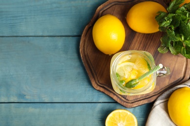 Cool freshly made lemonade and fruits on light blue wooden table, flat lay. Space for text