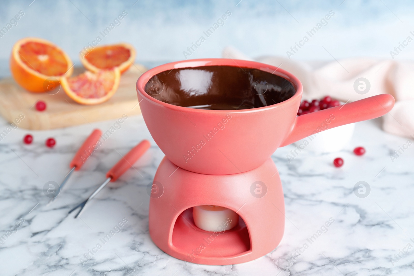 Photo of Ceramic pot with chocolate fondue on marble table