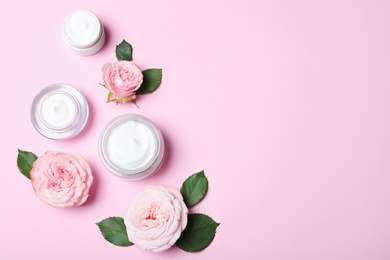 Photo of Flat lay composition with jars of organic cream and flowers on pink background. Space for text