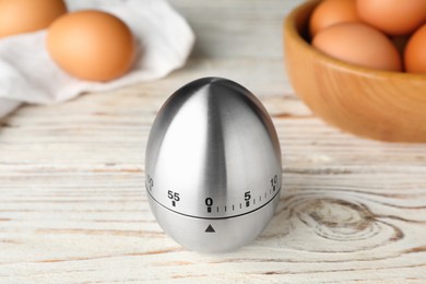 Kitchen timer and eggs on white wooden table