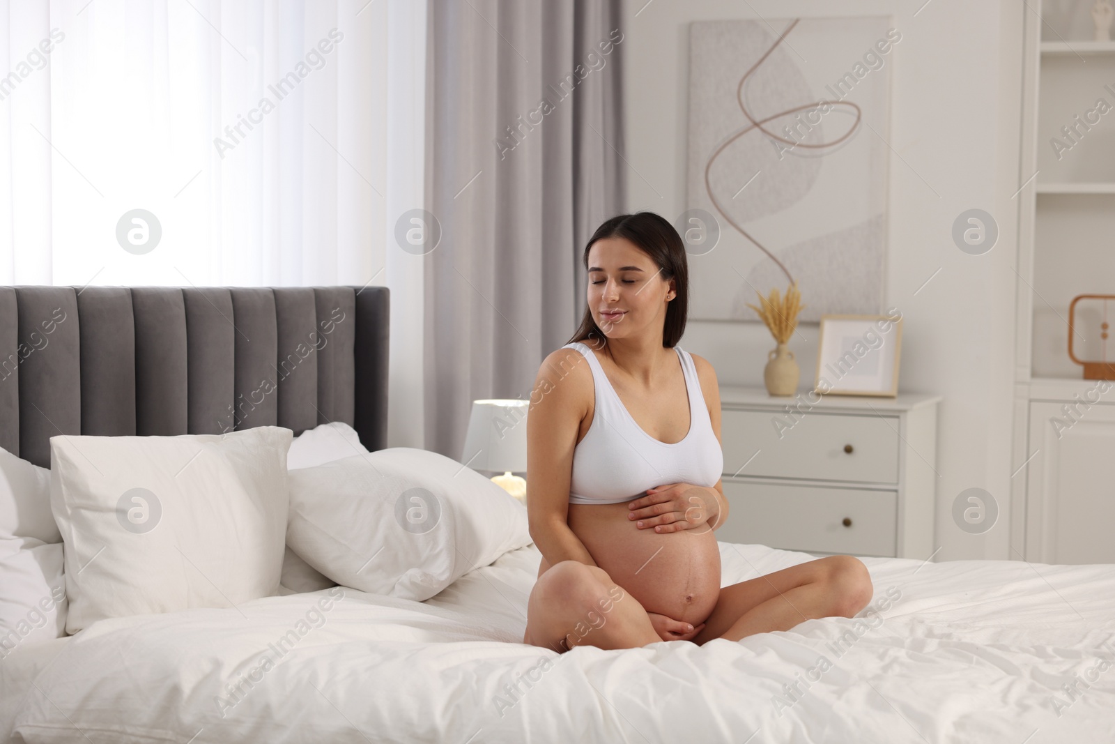 Photo of Beautiful pregnant woman in stylish comfortable underwear on bed at home