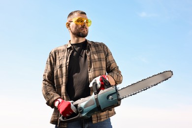 Photo of Man with modern saw against blue sky, low angle view