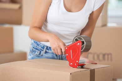 Woman packing box indoors, closeup. Moving day