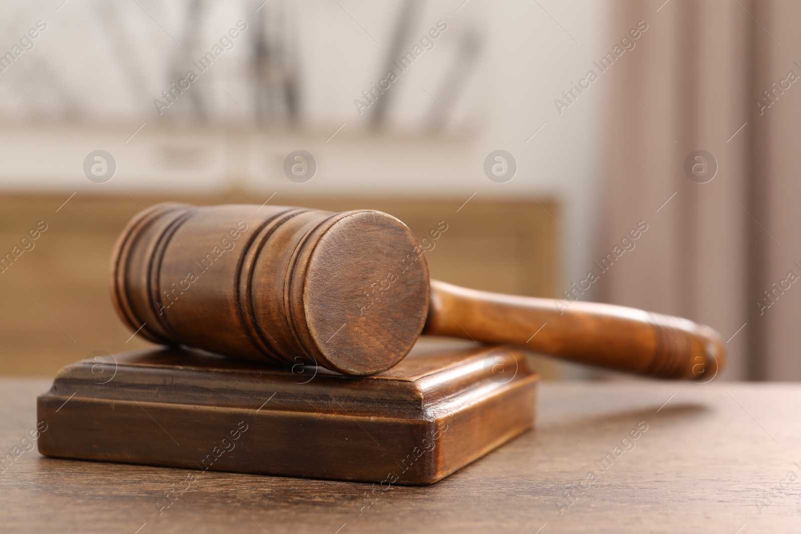 Photo of Wooden gavel and sound block on table indoors, closeup