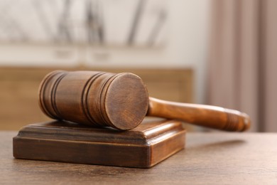 Photo of Wooden gavel and sound block on table indoors, closeup