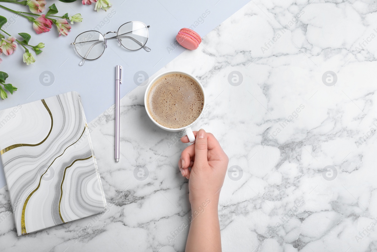 Photo of Woman with cup of coffee and stationery at marble table, top view. Space for text