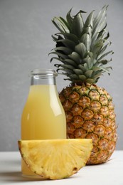 Photo of Delicious pineapple juice and fresh fruit on white wooden table
