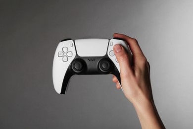 Woman with game controller on grey background, closeup