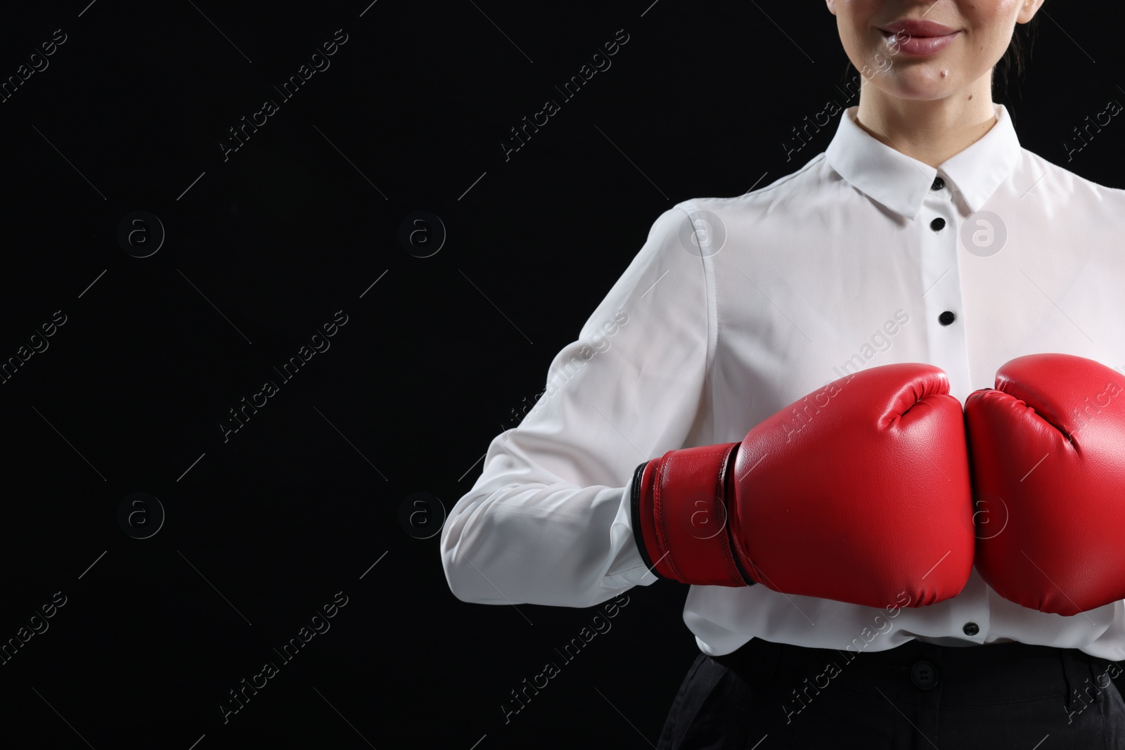 Photo of Businesswoman in shirt wearing boxing gloves on black background, closeup. Space for text