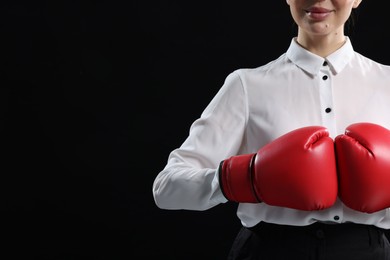 Businesswoman in shirt wearing boxing gloves on black background, closeup. Space for text