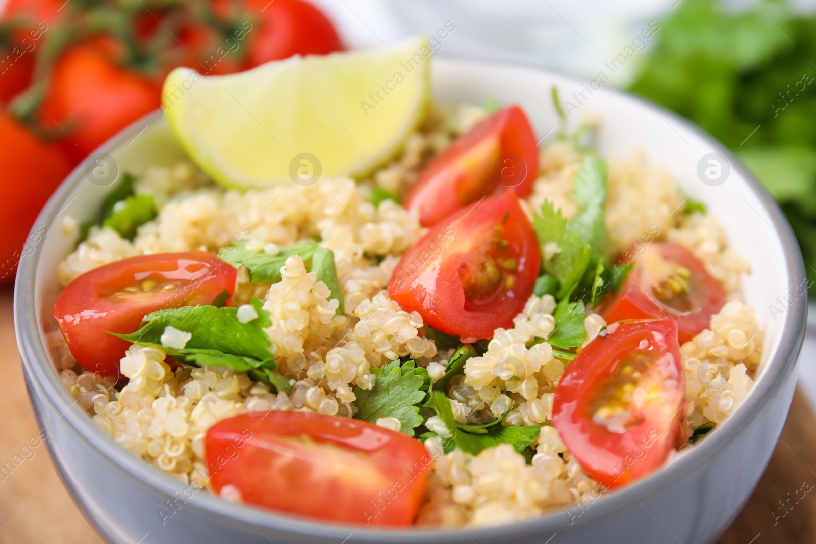 Photo of Delicious quinoa salad with tomatoes, parsley and lime, closeup
