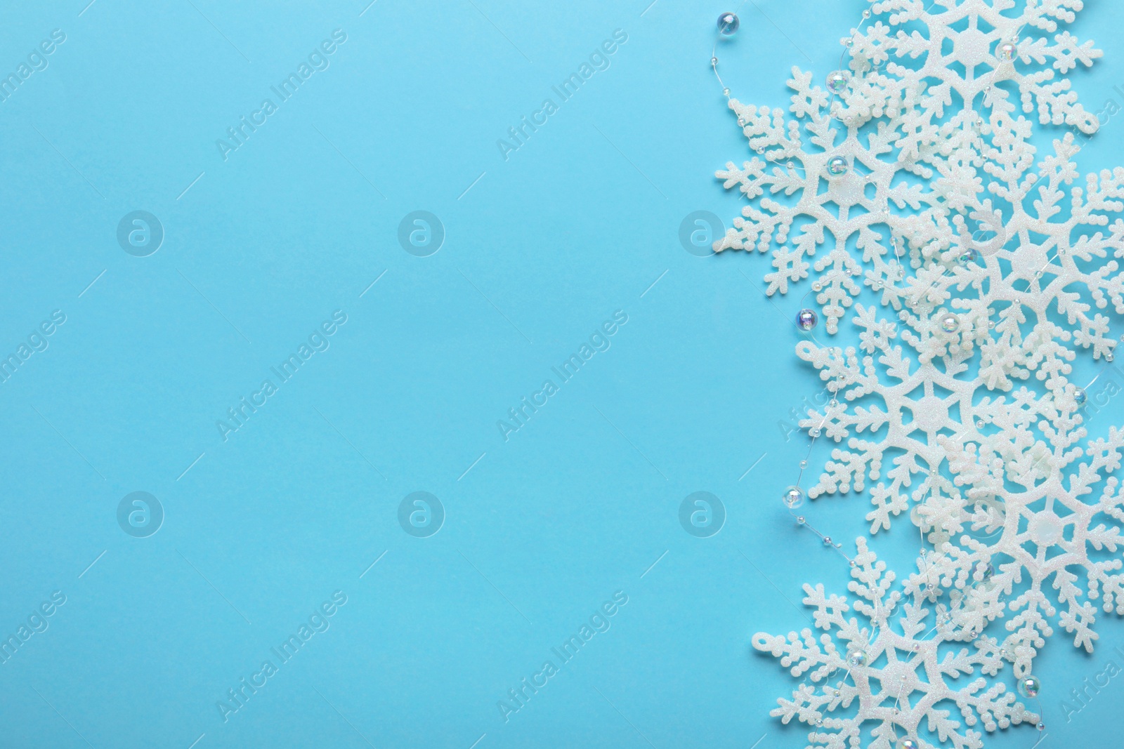 Photo of Beautiful snowflakes and decorative balls on light blue background, flat lay. Space for text