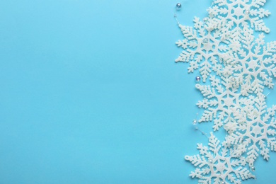 Beautiful snowflakes and decorative balls on light blue background, flat lay. Space for text