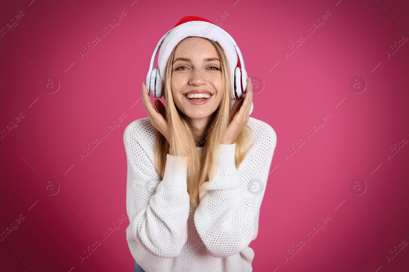 Photo of Happy woman with headphones on pink background. Christmas music