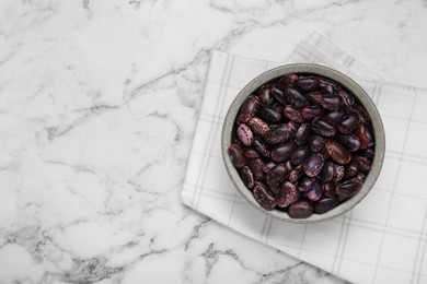 Photo of Bowl with dry kidney beans on white marble table, top view. Space for text