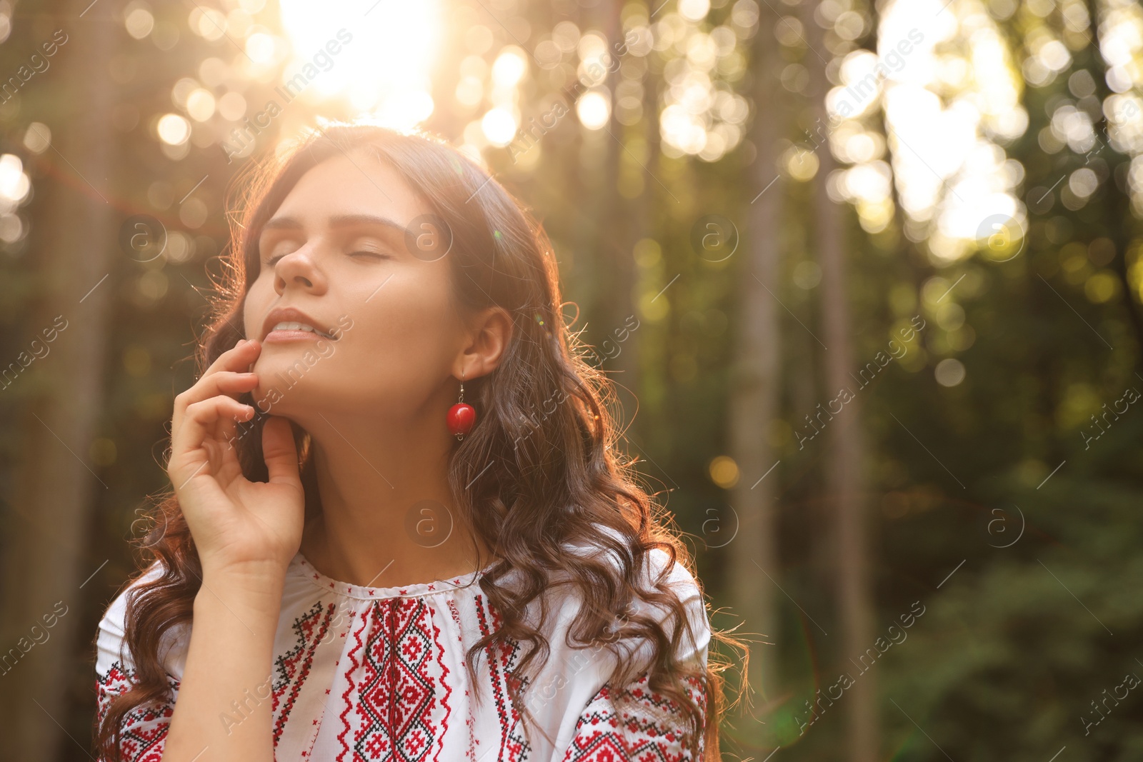 Photo of Beautiful woman in embroidered shirt outdoors on sunny day, space for text. Ukrainian national clothes