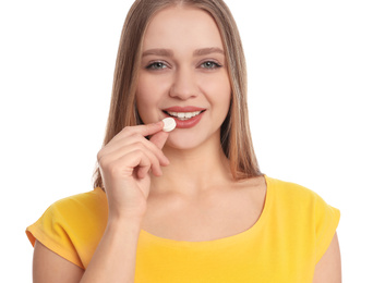 Young woman taking vitamin pill on white background