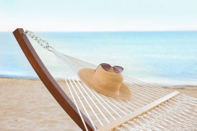 Photo of Comfortable hammock with straw hat and sunglasses at seaside