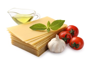 Photo of Stack of uncooked lasagna sheets, tomatoes, oil and garlic isolated on white